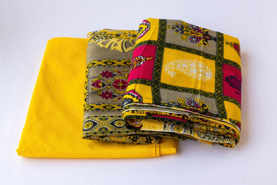 Folded yellow unstitched three-piece cotton fabric with traditional block print patterns. Isolated on white background. South Asian ethnic wear salwar kameez and dupatta set for women's fashion