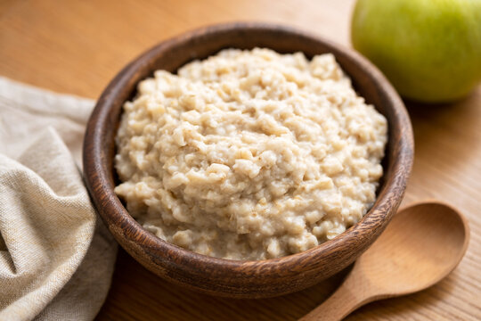 Healthy diet vegetarian breakfast: boiled oatmeal porridge in wooden bowl