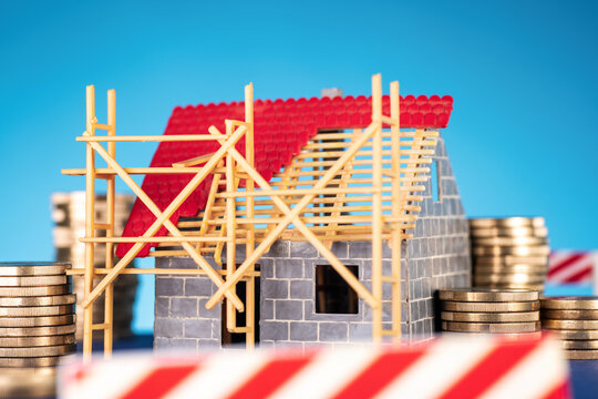 House construction and financing: shell construction with stacks of coins