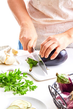 woman hands cutting an eggplant with a knife in a kitchen setting