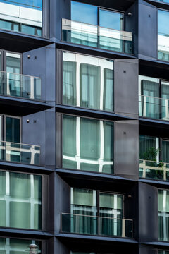 Modern architecture windows on a glass facade with repeating pattern grid in an urban building exterior suggesting apartment living and design