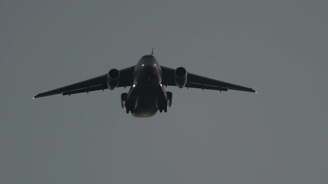 Military transport aircraft landing approach in overcast sky