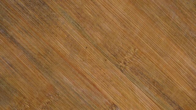 Rotating bamboo cutting board texture with visible grain and scratch marks
