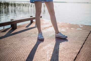 Female Legs in White Sneakers on Pier by the Lake