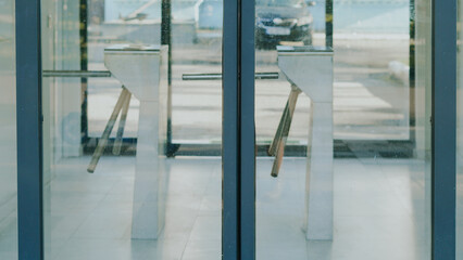 Turnstiles at entrance of modern building with glass doors and pavement