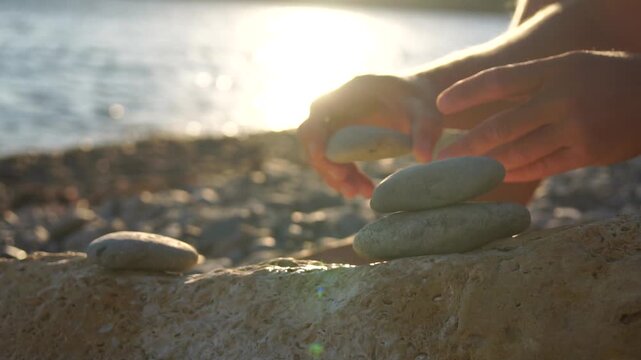 Building a Stone Cairn on a Beach at Sunset