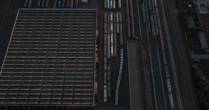 Aerial view of a train yard with multiple trains and a large building casting shadows in the evening light, Rome, Lazio, Italy.