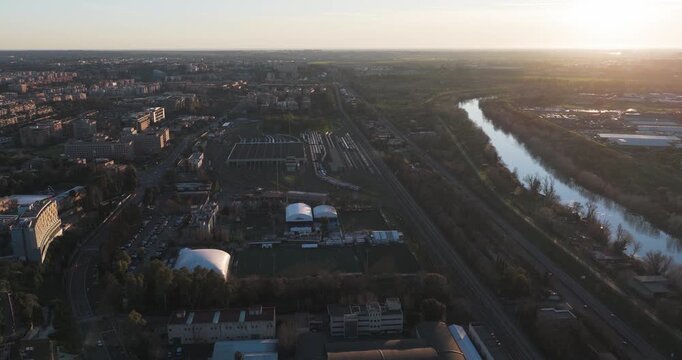 Aerial view of a tranquil river running alongside buildings and green spaces, contrasting urban and natural elements under a soft, diffused light, Rome, Lazio, Italy.