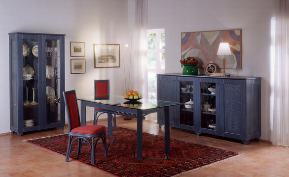 Single shot photo of a room with a rattan table, chairs and display cabinet