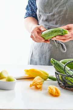 woman hands holding a zucchini in a kitchen setting
