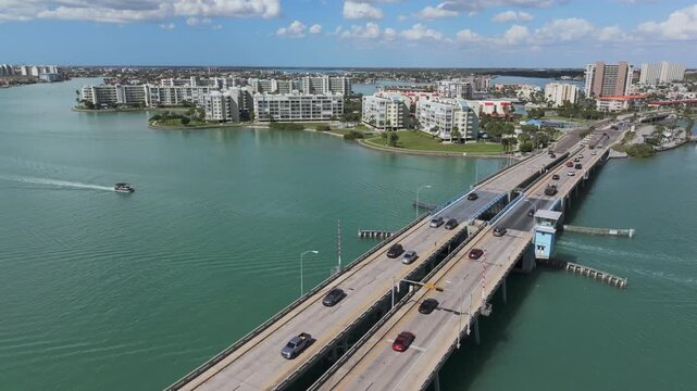 Aerial view of Corey Causeway drawbridge crossing turquoise Boca Ciega Bay waters, connecting waterfront condo communities with boat traffic in Saint Pete Beach, Florida's coastal corridor.