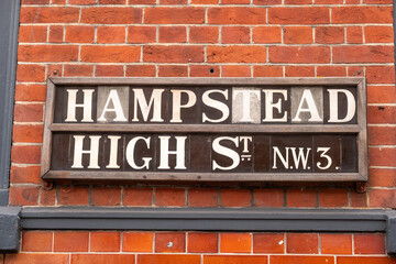 Obraz premium LONDON - 15 DECEMBER 2025: Hampstead High Street NW3 – Classic Street Sign on Brick Wall