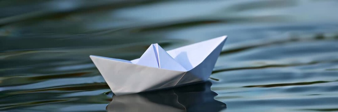 Paper boat floating on water surface with copy space, minimal travel dream video banner background, imagination freedom and journey concept.