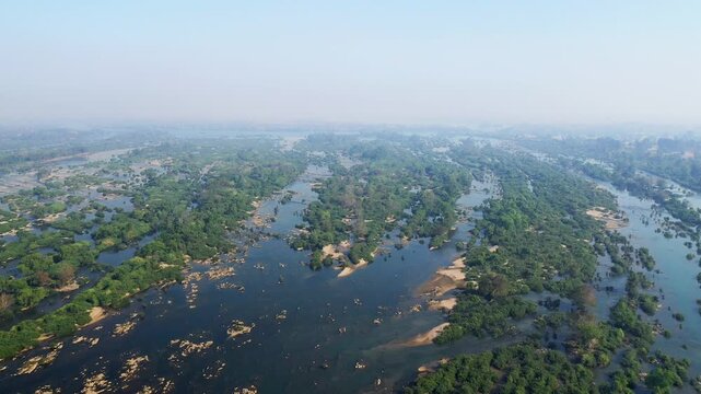 Scenic aerial shot of Li Phi Falls, also known as Tat Somphamit Waterfalls, surrounded by lush greenery and flowing water at sunrise in Laos.