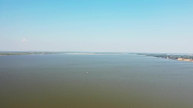 Aerial view of the expansive West Baray reservoir with calm water and distant shoreline under a clear blue sky in Cambodia.