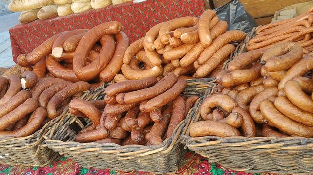 Stos kiełbas i wędlin na jarmarku, tradycyjne wyroby mięsne na sprzedaż, wiejska kuchnia i regionalne smaki.
