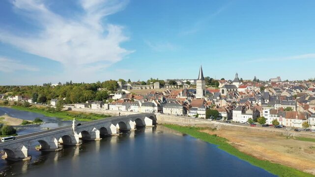 Aerial view of the picturesque town of La Charite sur Loire with its iconic stone bridge crossing the Loire River under a clear blue sky.