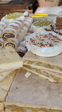 Ciasta na jarmarku, domowe wypieki na stoisku, makowiec i przekładane ciasto na sprzedaż, słodki poczęstunek w zbliżeniu.