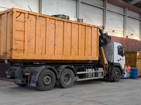 Mallorca, spain, february 20, 2026, roll off truck with large orange container for scrap metal recycling at waste management facility