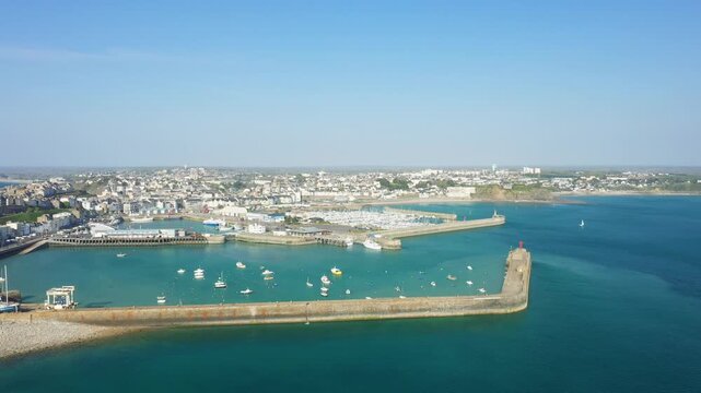 Scenic aerial view of Granville harbor with boats and a breakwater on a clear day, showcasing the coastal town and turquoise waters.