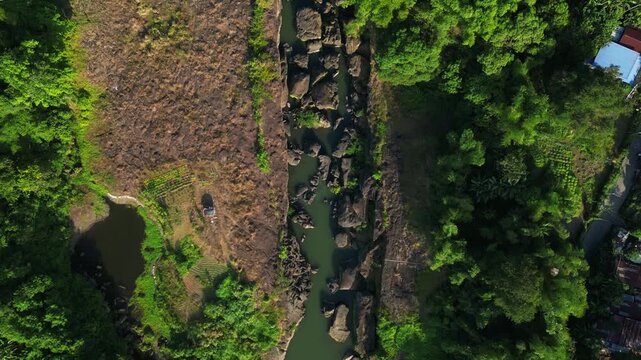 Wide daylight angle showing Bucal Tulay highway bridge crossing a rushing rocky river surrounded by tropical greenery in Maragondon Cavite Philippines.