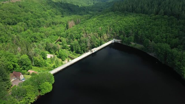 Drone shot of the Lac de Chaumecon dam surrounded by lush green forest, with tranquil water and scenic natural landscape in Burgundy, France.