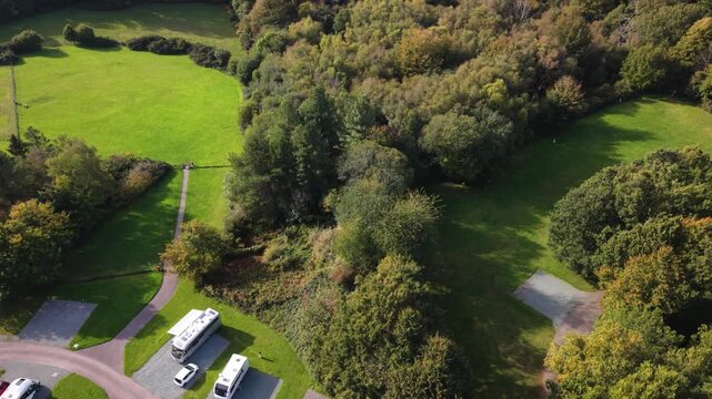 Rookesbury Park Wickham Hampshire tree top dropping circling drone footage at Caravan and Motorhome Club campsite in wooded setting of the Bere Forest with Autumn trees in bright sunlight