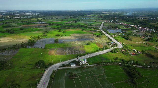 Wide daytime view of a provincial road crossing rice fields and green landscapes in Muzon Naic Cavite Philippines.