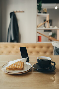 Lunch break in a cafe interior. Coffee sandwich and smartphone.