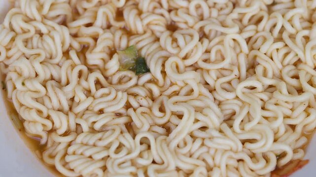 Instant noodle snapshot. Highlighting crunchy noodles with central vegetable fragment. Vivid portrayal of quickcook noodles with textured pattern and appealing appearance
