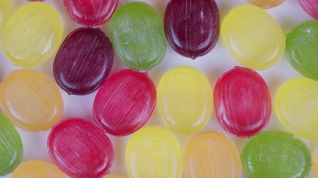Colorful candy closeup. Closeup of shiny multicolored round candies against white background. Detailed macro photograph of vividly colored sugarcoated candies in various hues