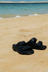 Fototapeta premium a pair of black shoes on the beach during summertime sunny weather