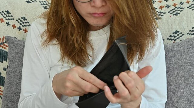 Woman having stress while she try to finding money in her empty wallet. Having financial problems means being unable to pay debts over the short or long term.