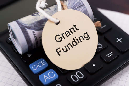 Grant funding text on a round paper note with money roll and calculator