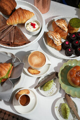 Luxury Breakfast Spread with Pastries, Coffee, and Gourmet Breads. Table setting featuring croissants, caneles, coffee latte, espresso, pastries served with pistachio butter in cafe or hotel setting