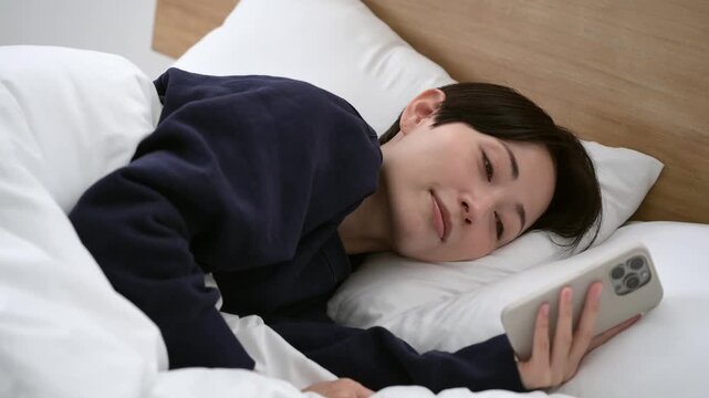 ベッドでスマホを見る女性