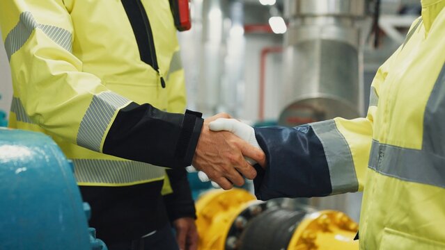 Close-up shot of Two engineers shake hands after completing an after-hours HVAC inspection, confirming work acceptance and safety compliance.