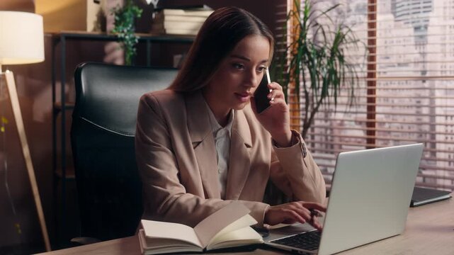 Caucasian business woman talking mobile phone call typing laptop writing notes multitasking occupation at office table female girl worker businesswoman multitask work in company talk smartphone write