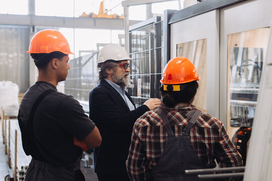 Manager instructing factory workers on window production line