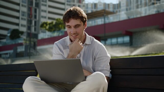 Pensive smiling Caucasian business man looking in laptop thinking businessman with computer think smile manager entrepreneur employer working remote work with online website in city sitting on bench