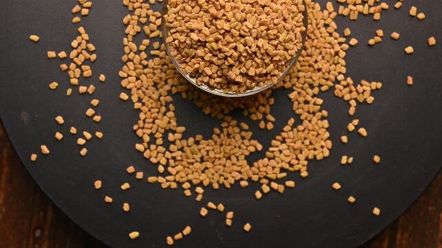 Top View of Methi Seeds (Fenugreek) in White Bowl on Black Background &ndash; Rotating Footage