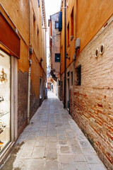 Naklejka premium Narrow walkway between buildings in a historic area with shops and stone pathways