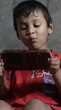 A mother feeding her child by hand while the child watches a mobile screen