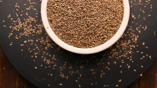 Top View of Carom Seeds (Ajwain) in White Bowl on Black Background &ndash; Rotating Footage