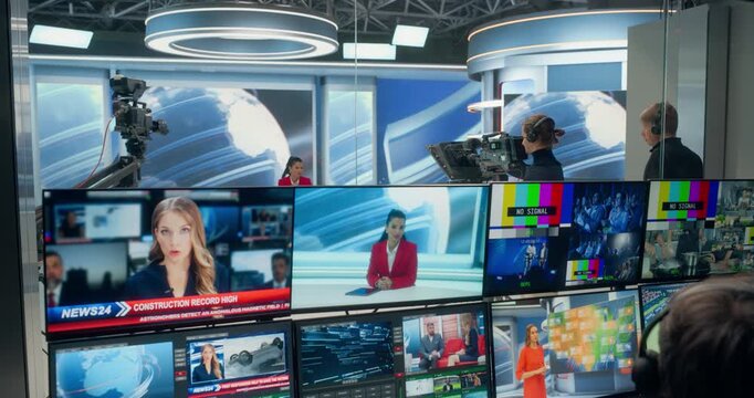 Backstage TV Station Production Control Room Coordinates a Live News Reportageas Operators Monitor Multiview Screens, Switch Studio Camera Feeds, Check Signals, Female Anchor Delivering Updates 