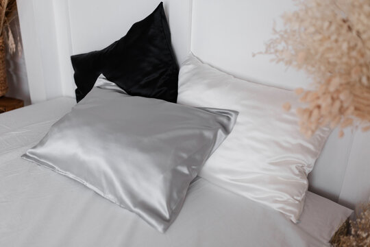 Silver, white and black silk pillowcases on a white bed