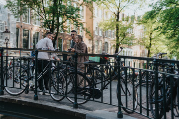 Three friends stand by parked bicycles on a canal bridge in Amsterdam. They chat casually beside a row of bikes against a leafy urban backdrop.
