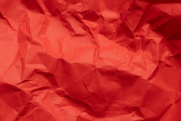 Fototapeta premium Crumpled Red Paper Texture Background,Top view of vivid red crumpled paper texture background. Abstract background of wrinkled paper surface with shadows and creases, ideal for wallpaper, design.
