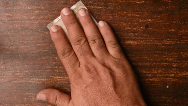 Top View of Man Placing 500 Rupee Notes One by One on Wooden Table
