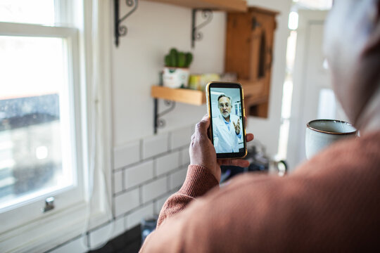 Man video calling doctor in home kitchen